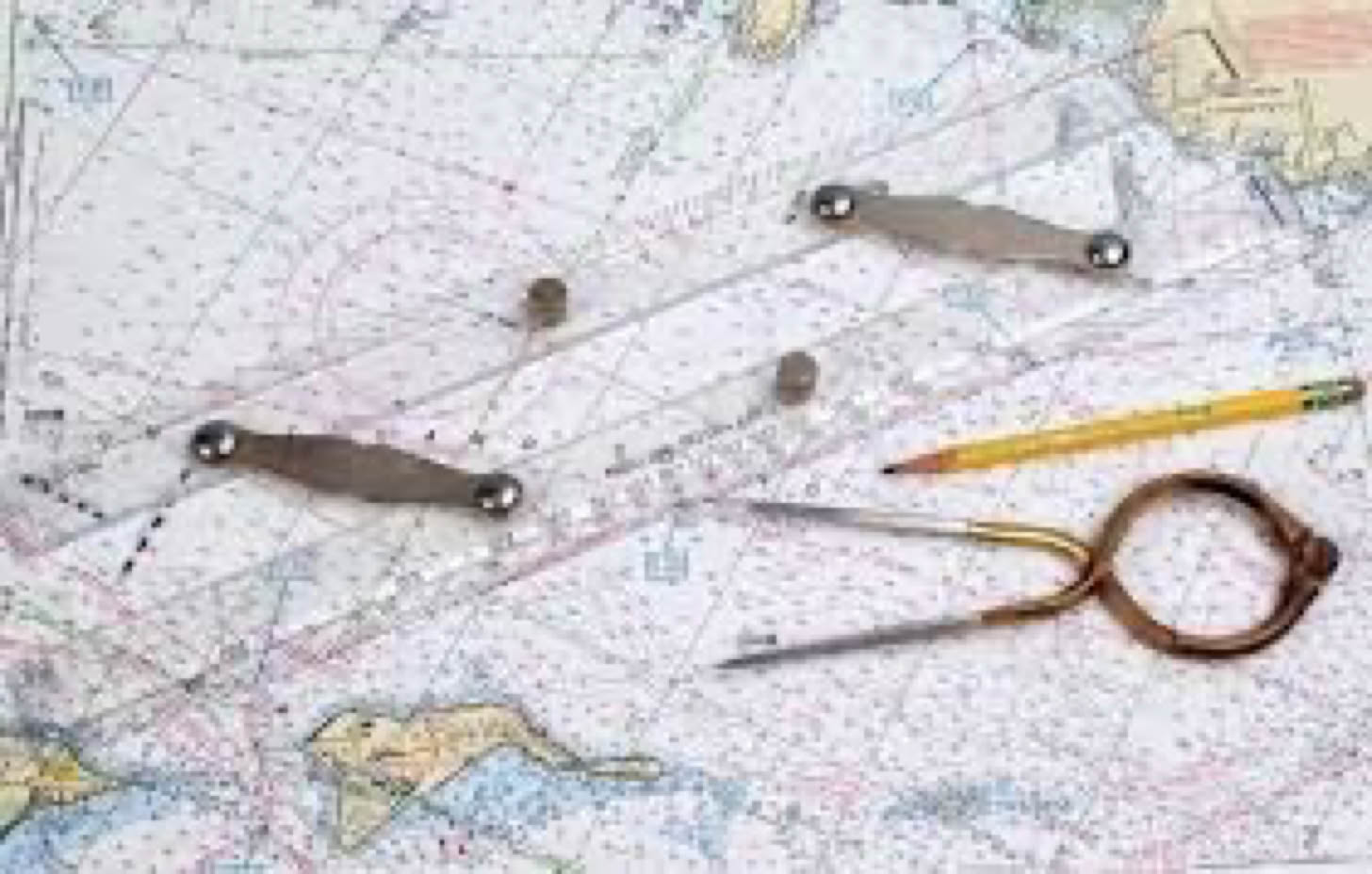 A nautical chart with parallel rulers, a pencil, and a pair of dividers placed on top.